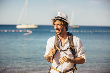 Outdoor fashion portrait of handsome stylish tourist man posing at the beach.