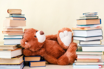 Stuffed toy Teddy bear lies among the stacks of books and dreams the concept of baby learning