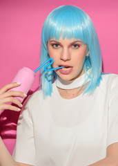 Portrait of young woman with blue hair drinks soda bottle on pink background. Pink metal aluminum beverage drink can. Summer boring, tedious party poster