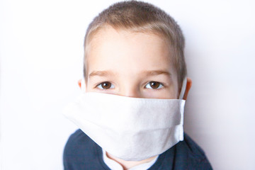 Boy child with big brown eyes wearing medicine disposable mask, white background