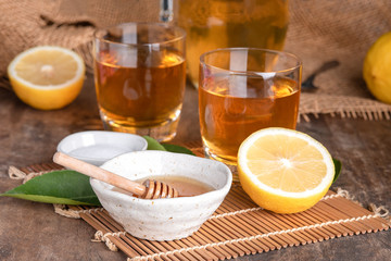 A glass of iced tea with mint and lemon on a wooden table.A glass cup of tea with lemon, mint, and honey on a wooden rustic table.