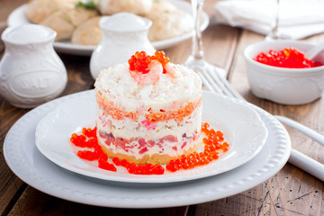 Holiday salad with red fish, shrimp, crab sticks, vegetables and red caviar, selective focus