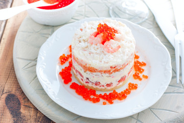 Holiday salad with red fish, shrimp, crab sticks, vegetables and red caviar, selective focus