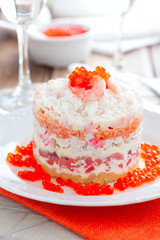 Holiday salad with red fish, shrimp, crab sticks, vegetables and red caviar, selective focus