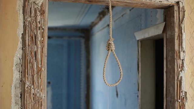 A suicide rope loop hangs in an abandoned wooden house. Preparing for suicide by hanging.