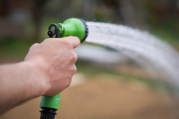 The man is preparing his garden at the cottage for the summer and hopes to have a rich harvest. Detail of his hand with working tool on the blured background.
