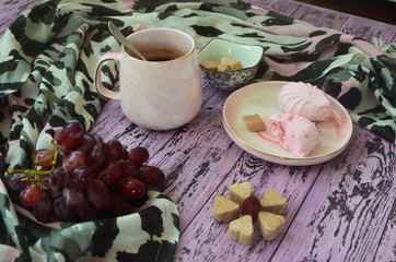 A cup of coffee, marshmallows, grapes and refined sugar on a wooden table. Morning breakfast no people