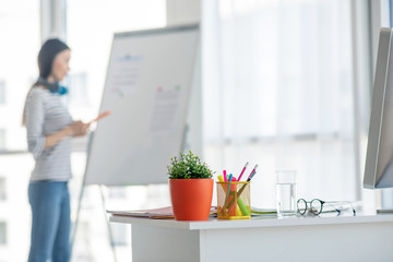 Dark-haired woman in jeans standing near the flipchart