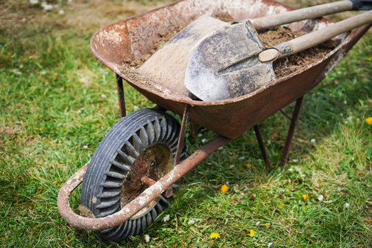 Detail of wheelbarrow with some working tools and clay. Topic of the prepare garden at the cottage for the summer and hope to have a rich harvest.