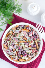 Salad with red beans, smoked sausage, cheese and crackers in a white bowl, selective focus