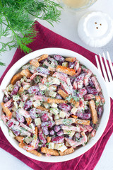 Salad with red beans, smoked sausage, cheese and crackers in a white bowl, selective focus