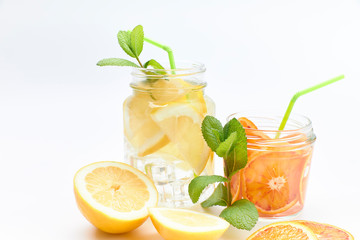 Pitcher and glass of homemade lemonade and orangeade with some mint leaves