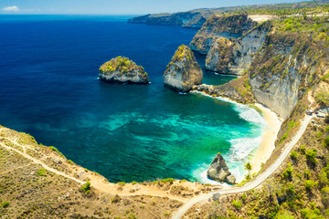Traveler hiker standing on the top of mountain cliff and enjoy amazing nature landscape with scenery tropical beach and clear sea water. Bali, Indonesia. Aerial view.