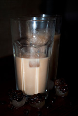 Coffee with cold milk in a glass with  in the background with burlap. Iced coffee with ice cube, frozen chamois coffee.
