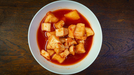 Korean Radish Kimchi in white bowl on wood table for food content.