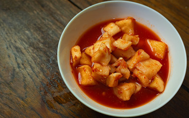 Korean Radish Kimchi in white bowl on wood table for food content.