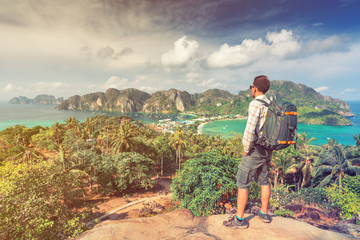 Travel man with photo backpack enjoy amazing view nature landscape island phi-phi from top of mountain at sunrise. Active lifestyle and Travel concept