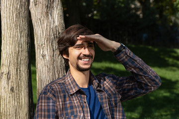 Young brunet man with beard and mustache sitting smiling looking at the screen of a smartphone