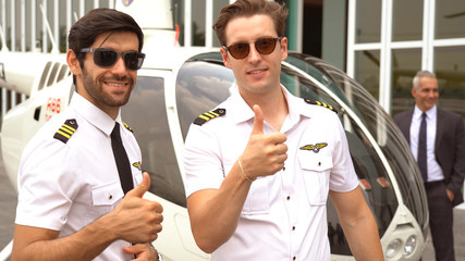 Pilot in uniform standing near small private helicopter