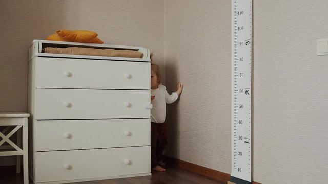 Cheerful cute baby girl playing hide and seek at home. Children funny game.