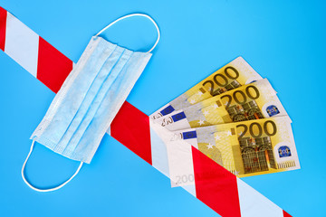 Money in euros and a medical mask on a blue background. Concept problems in Europe due to coronavirus quarantine. Crisis european financial system due to economic under the epidemic of the flu virus