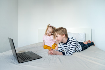 Girl and boy using laptop amd earphones at home