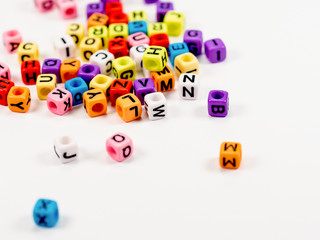 Colorful alphabets beads on white background, selective focus. concept image