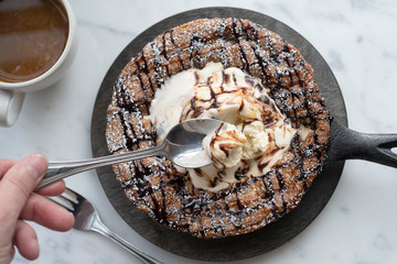 Spoonful of whipped cream from an Ice Cream Brownie desserts on a. marble background