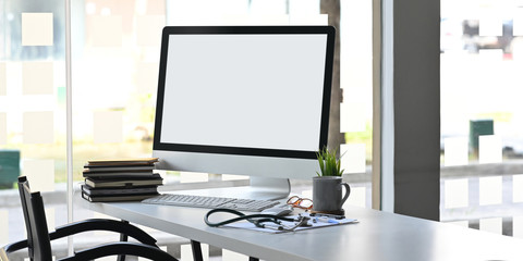 Computer monitor with white blank screen putting on doctor working desk together with stack of...