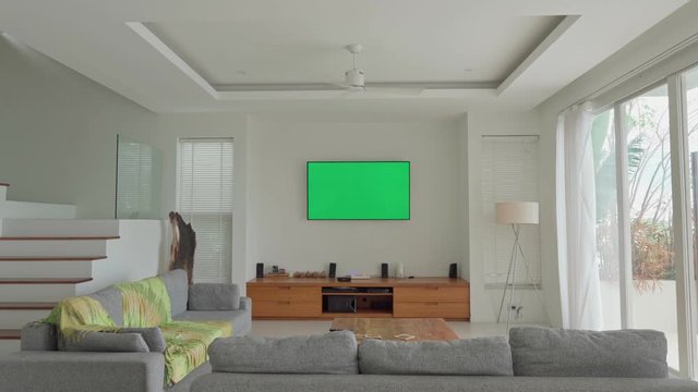 LCD TV with green screen on the wall in modern living room with spinning ceiling fan