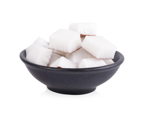 The coconut meat is cut into squares in a black cup ready for cooking. Isolated on white background