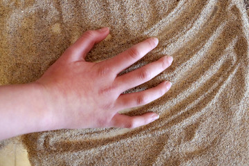 Sand therapy, children's hand draws on a glass transparent table with sand
