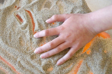 Sand therapy, children's hand draws on a glass transparent table with sand
