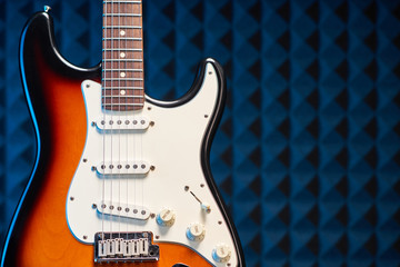 Fototapeta na wymiar Sunburst electric guitar standing over acoustic foam panel background