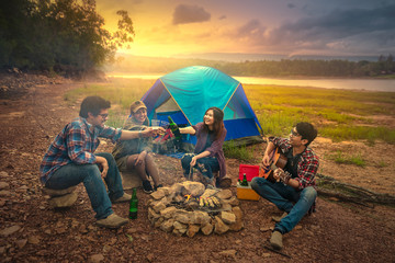 Happy friends camping party playing music and enjoying bonfire in nature and lake, Traveler camping...