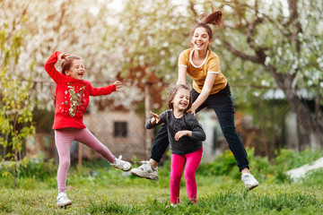 happy little girls sisters and twins jumping and playing in the garden with grass