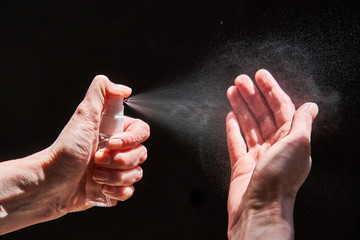 Fototapeta na wymiar Hand spraying sanitizer over black background