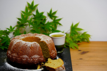 Homemade bund cake with  a piece cut out and a cup of green tea. 