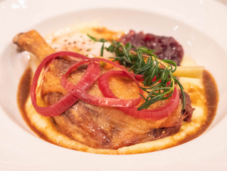 baked Duck leg with sauce on white plate
