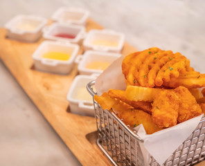 French fries in basket with  sauce on wooden plate