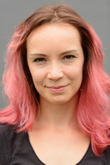 Fototapeta premium Face of beautiful woman with pink hair against gray wall