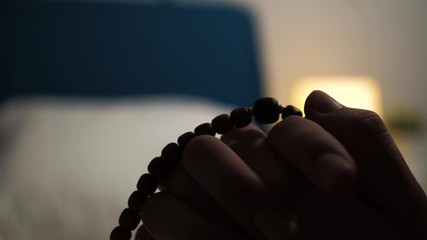 Prayer. Female hands hold rosary and sort beads one by one. Close-up