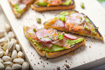 salmon toast with gacamole, radishes and bean sprouts