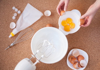Step by step recipe of meringue cookies. Step 3. The girl breaks the egg and puts the egg yolks in a separate bowl. Preparation of cream and dough for dessert
