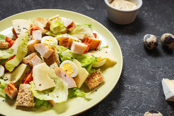 Fresh Caesar salad with delicious chicken breast, ruccola, spinach, croutons, egg, parmesan and cherry tomato on stone background.