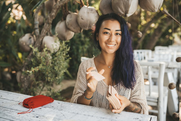Woman is reading Tarot cards sitting at the table outdoors