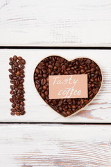 Tasty coffee love concept. Coffee beans in a shape of heart and letter I. White wood background.