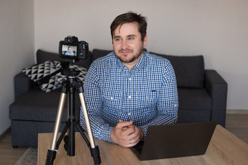 Nice content young man smiling and making a video at home. Working for you.