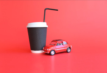 Design concept of mockup coffee cup and little red toy car isolated on red background. Copy space for text