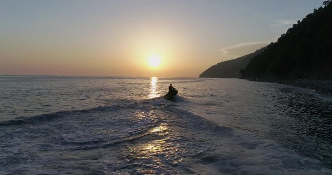 AERIAL TOP: Jet ski is sailing on the sea under sunset. sport riding a personal watercraft. stunt riding on jet ski. riding a new model of water bike on the sea. Sports and holidays